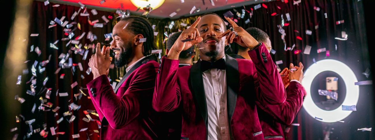Guests in tuxedos with a confetti burst on a 360 video booth platform