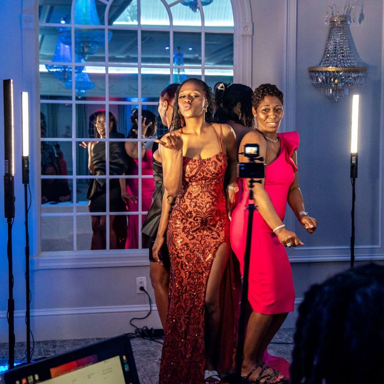 Two guests in evening dresses posing dramatically for the 360 video booth at a glamour event