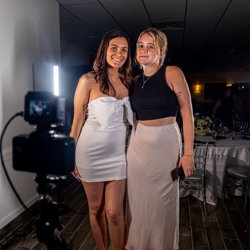 Two wedding guests in evening wear posing on the 360 video booth platform, camera arm in foreground