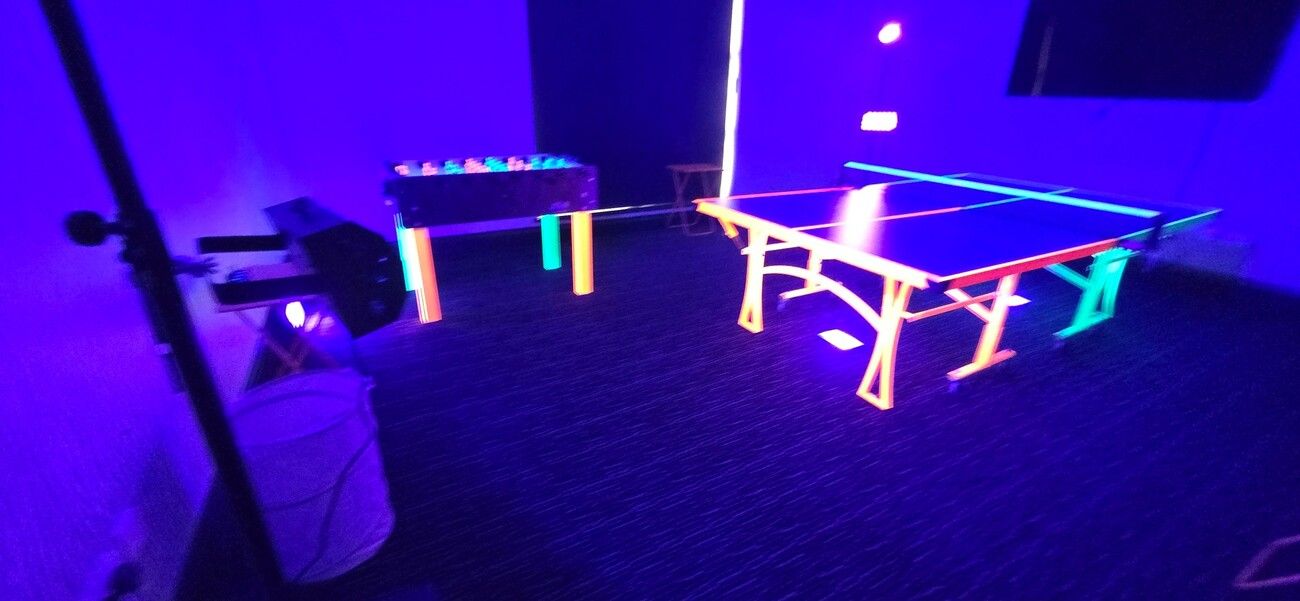 Our UV games room under blacklight with the glowing table football and table tennis tables