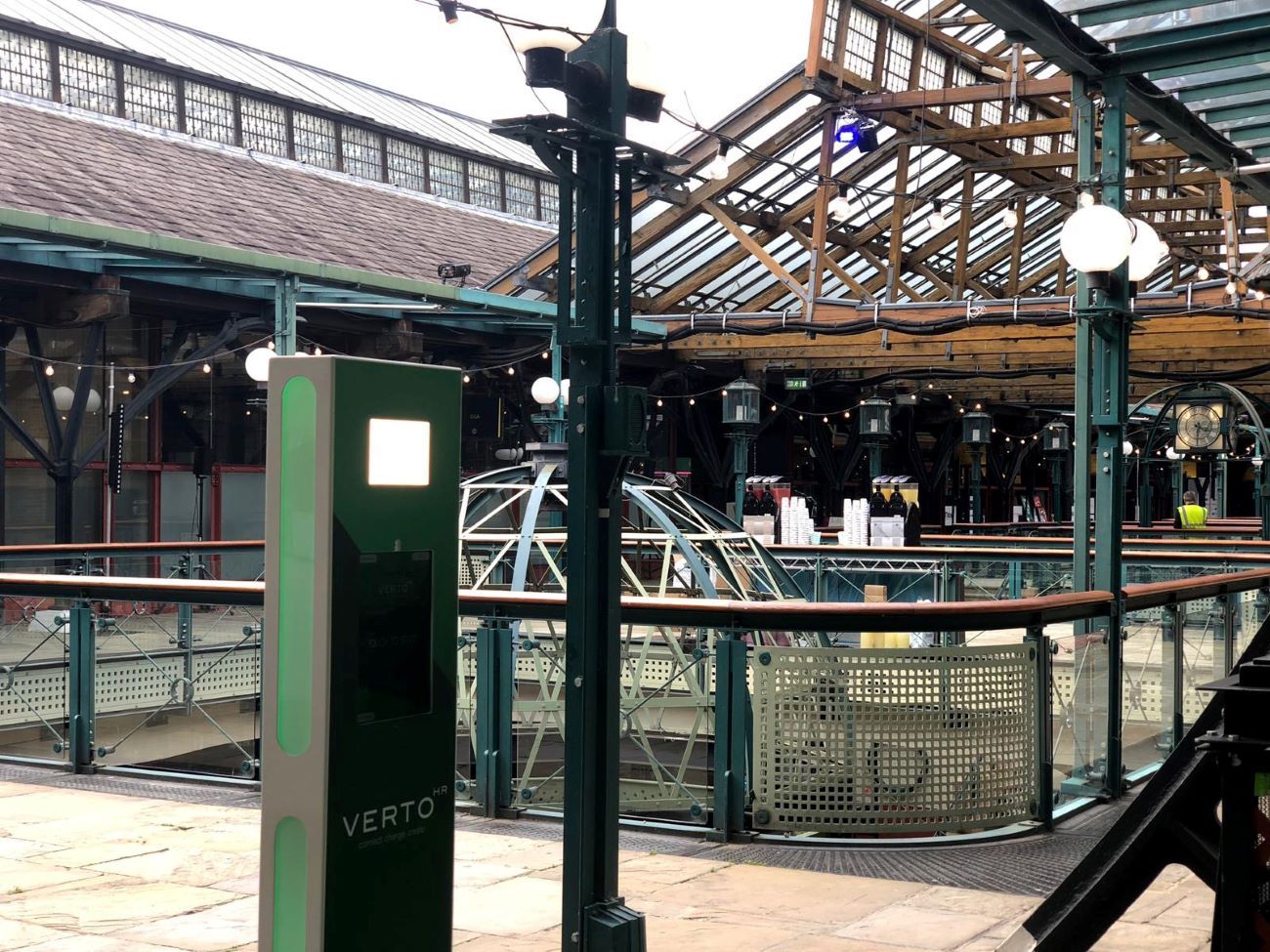 VERTO — green floor-mounted totem booth in a covered marketplace