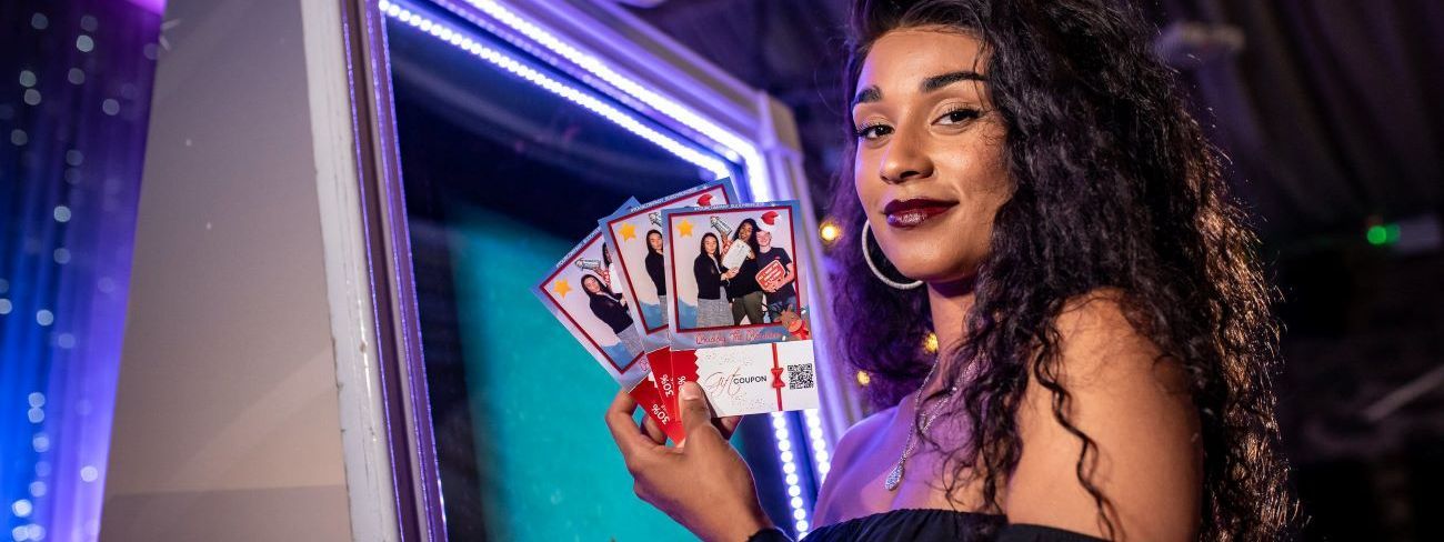 A guest holding personalised instant photo booth prints at a party