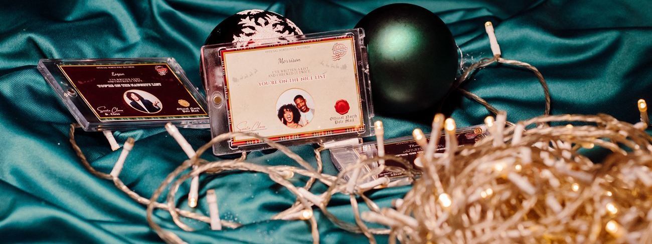 Naughty and nice list certificate cards in display cases arranged among baubles and fairy lights