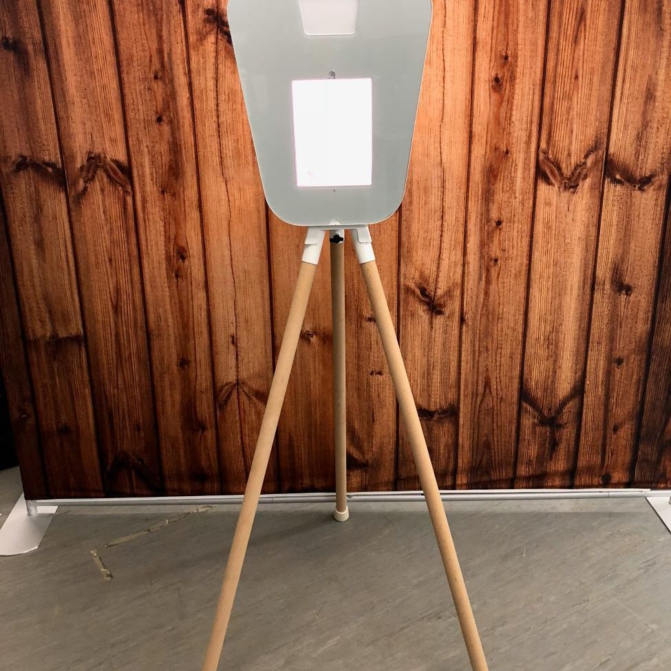 Reverse view of the retro pod on its wooden tripod against a dark wood-panelled wall, showing the white back of the screen housing