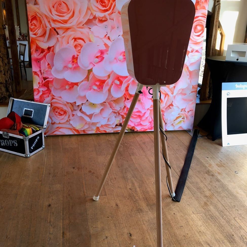 Back-of-fascia view of the retro pod next to a pink-and-white flower wall backdrop, with the props case visible to the side