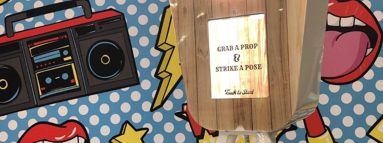A retro pod photo booth in front of a pop-art comic-style backdrop
