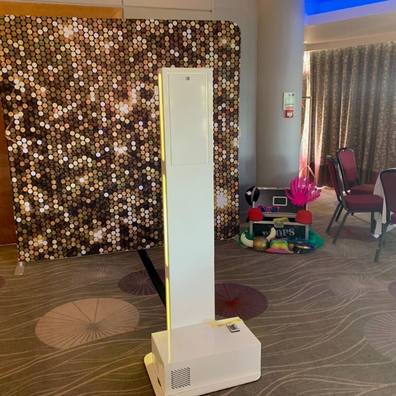 Selfie pod paired with an audio guestbook against a gold sequin backdrop in a hotel ballroom
