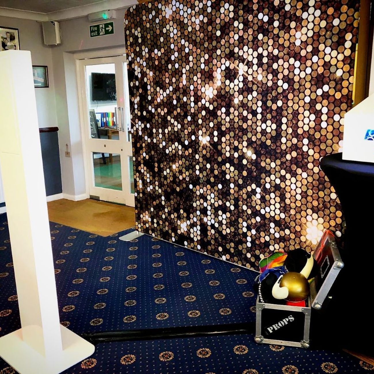 Selfie pod set up next to a gold sequin sparkle backdrop in a country-house hotel venue, props case visible to the side