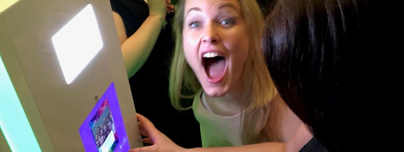 A guest laughing at the touchscreen preview of a selfie pod photo booth