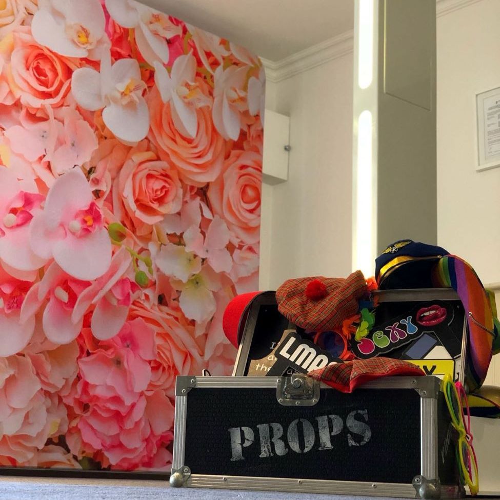 Close detail of the selfie pod's LED light strip alongside a pink floral wall backdrop, props case in the foreground