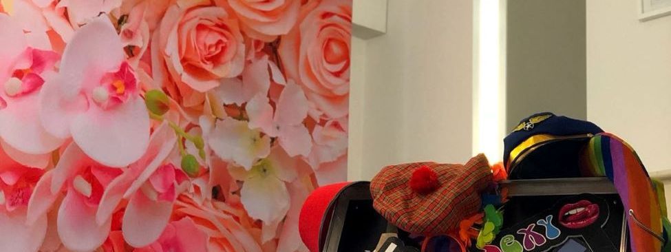A selfie pod photo booth lit up in front of a floral wall backdrop