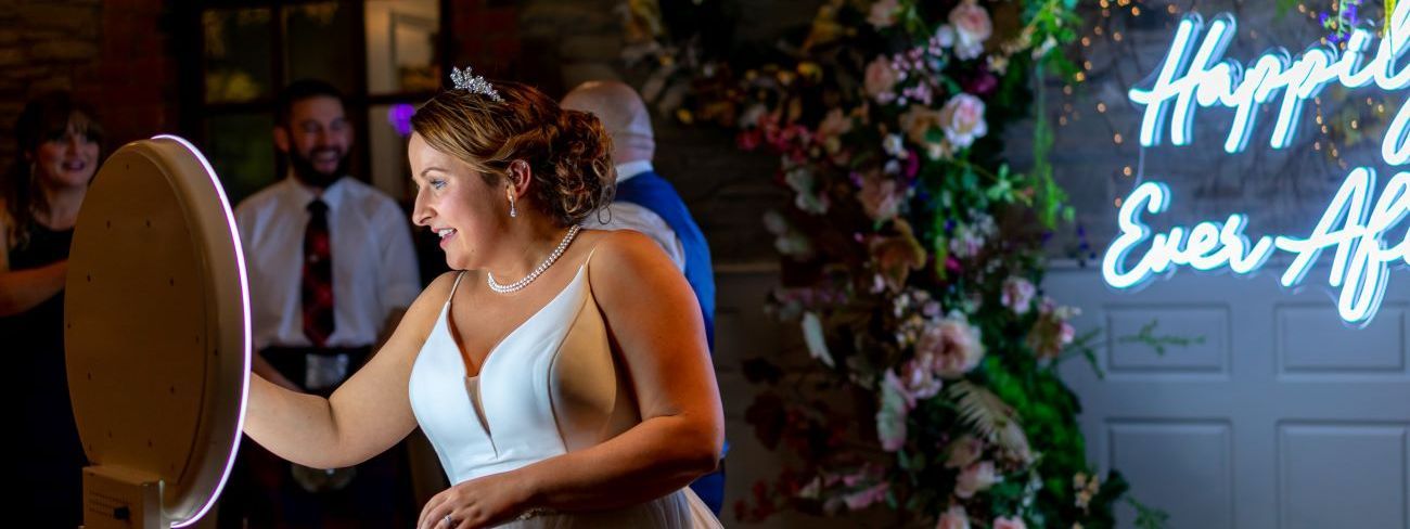 A photo booth with a happily ever after neon backdrop at an engagement celebration