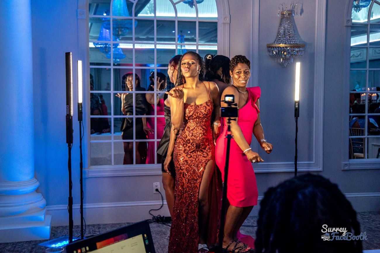 Two guests in evening dresses posing dramatically for the 360 video booth at a glamour event