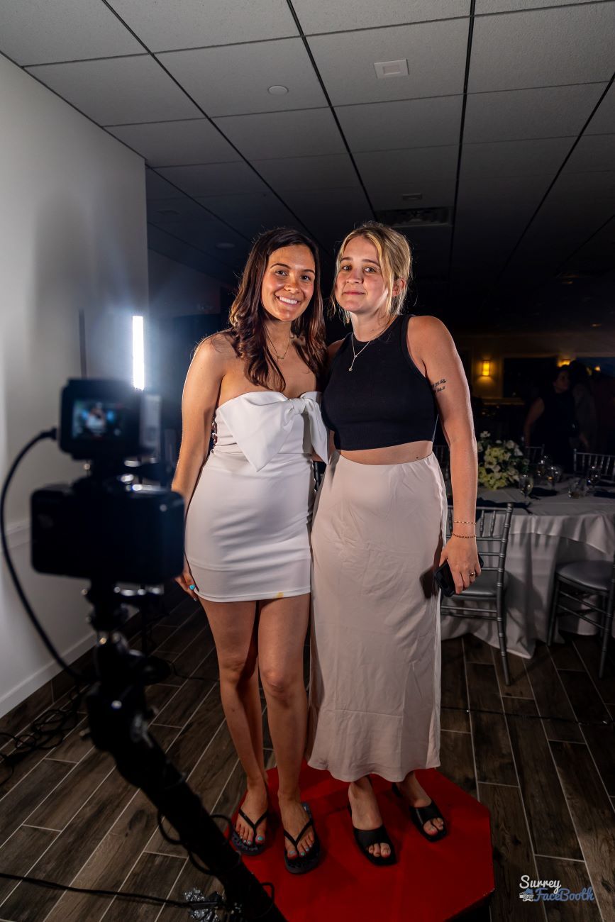 Two wedding guests in evening wear posing on the 360 video booth platform, camera arm in foreground