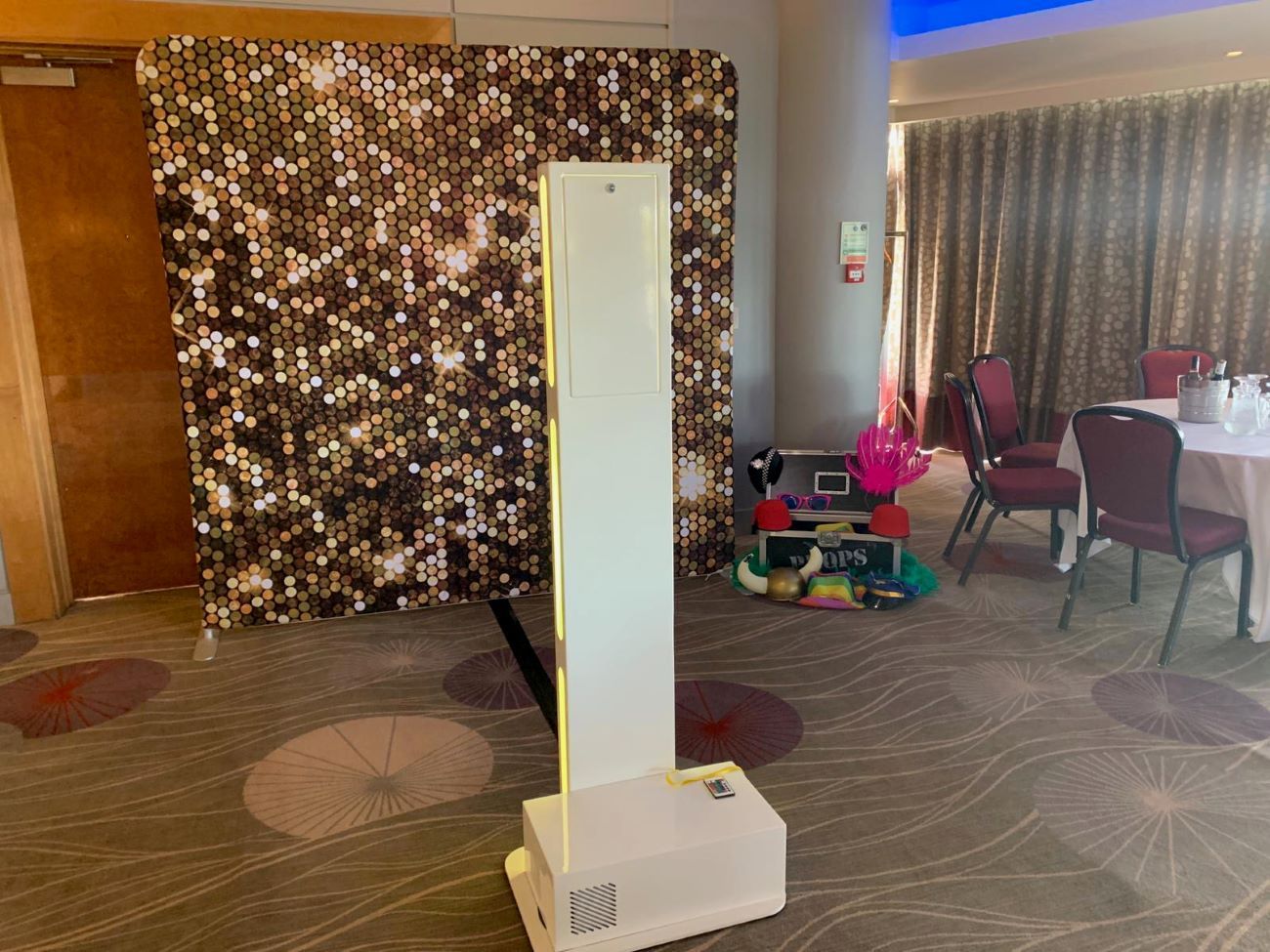 Selfie pod paired with an audio guestbook against a gold sequin backdrop in a hotel ballroom