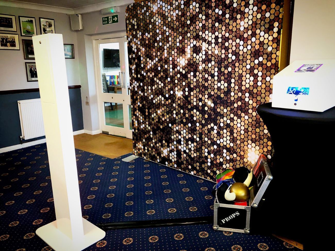 Selfie pod set up next to a gold sequin sparkle backdrop in a country-house hotel venue, props case visible to the side