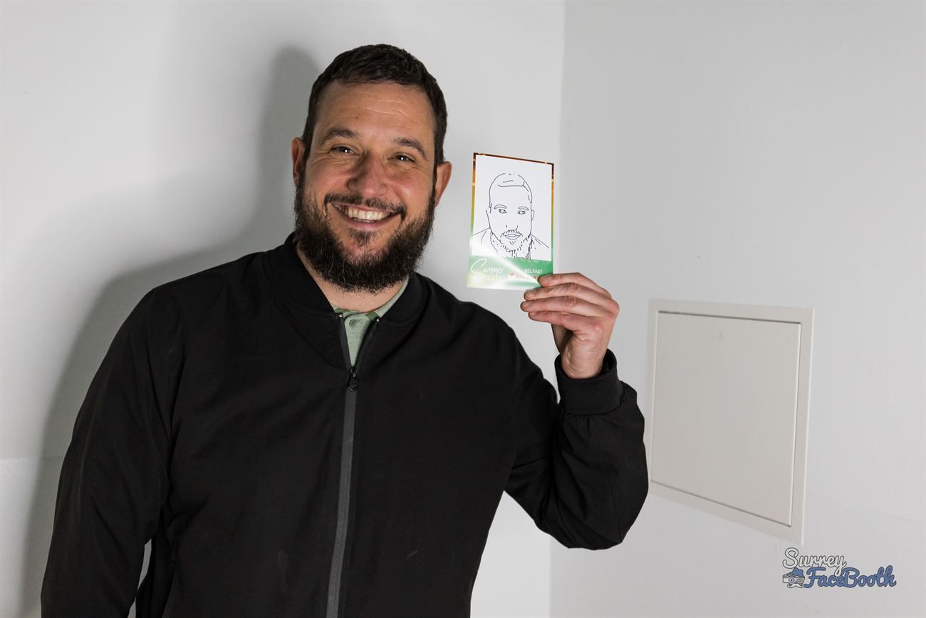 Smiling guest holding his finished hand-drawn portrait on a branded card