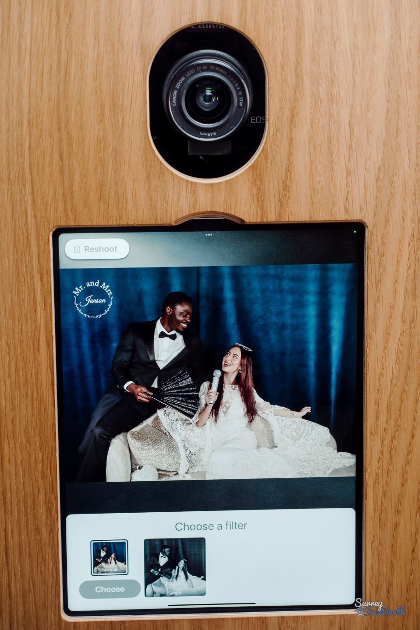 Detail shot of the vintage photo booth's Canon EOS DSLR camera and touchscreen, showing the post-capture filter-selection screen with a wedding monogram overlay for Mr and Mrs Jenson
