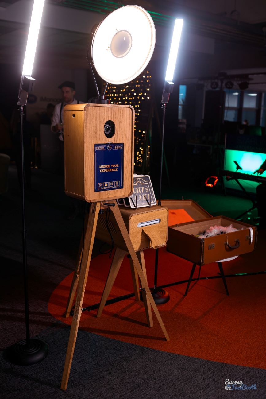 Vintage photo booth set up at a corporate Gatsby-themed event with the 'Choose Your Experience' selection screen, vintage suitcase prop box and ritz-style print frames alongside