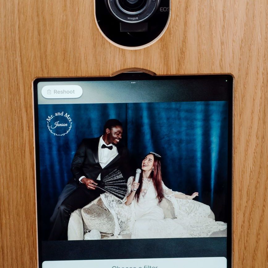 Detail shot of the vintage photo booth's Canon EOS DSLR camera and touchscreen, showing the post-capture filter-selection screen with a wedding monogram overlay for Mr and Mrs Jenson