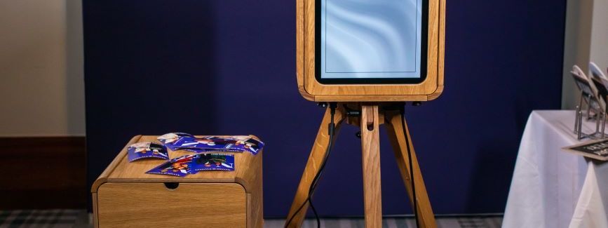 A vintage wooden photo booth set up at a wedding with a print cabinet